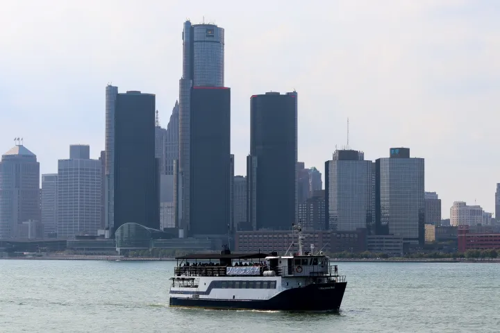 a large ship in a body of water with a city in the background