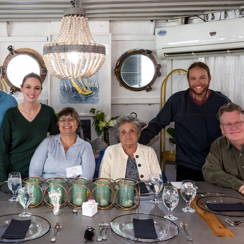 Jayson Brinkler et al. sitting at a table with wine glasses