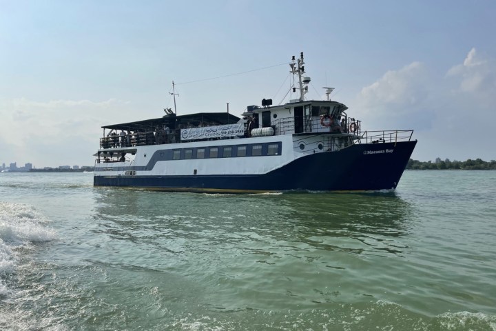 A passenger ferry navigating calm waters under a partly cloudy sky.