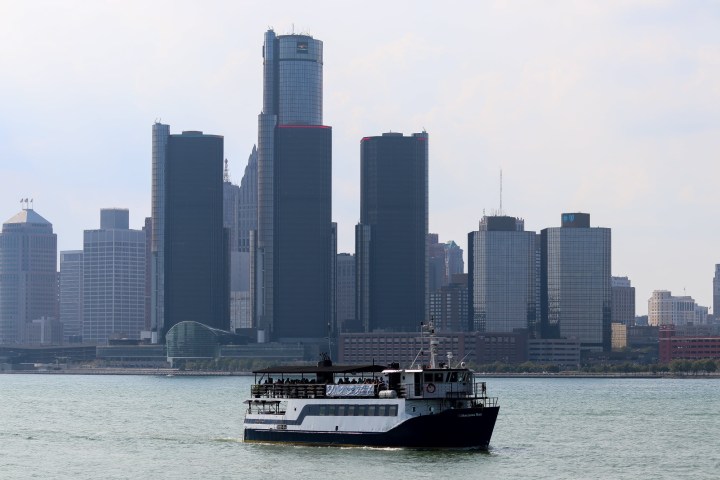 Boat on river with city skyline in the background.